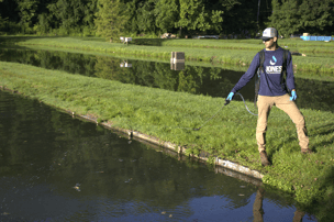 man spaying algae in pond