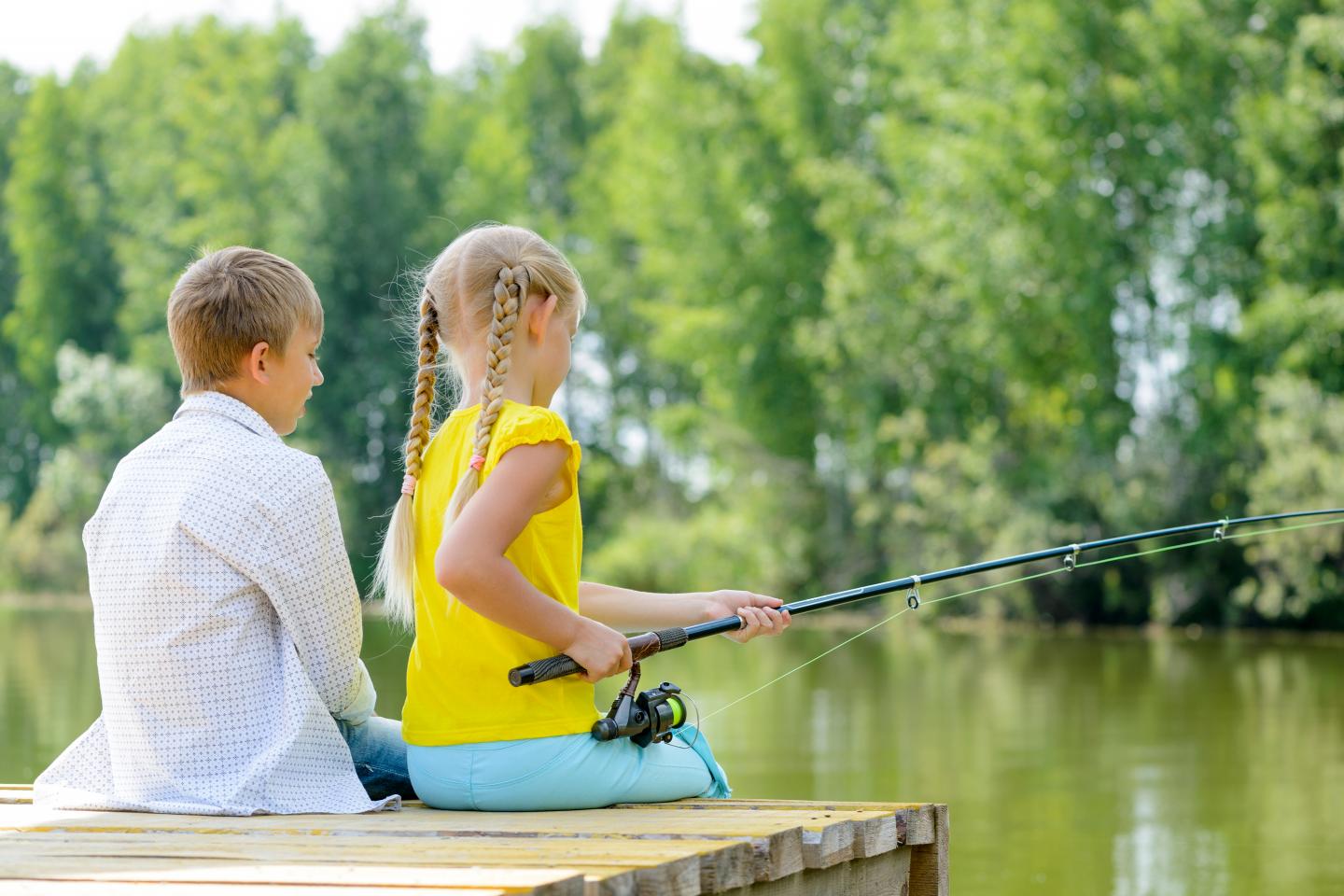 two children fishing pond from wooden dock