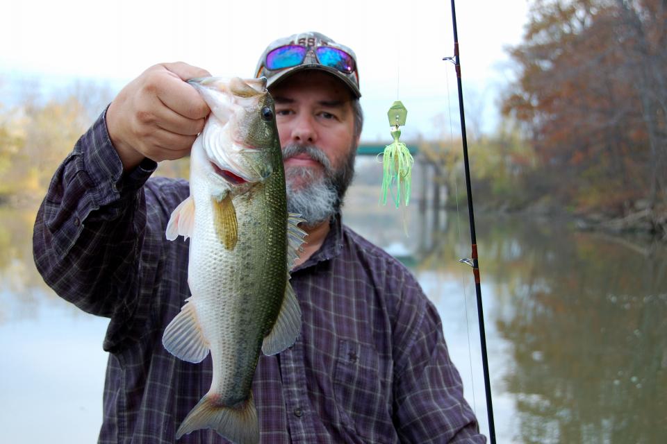 Angler holds his largemouth bass in front of his face