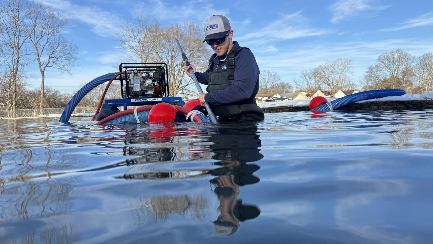 A biologists uses a small, floating hydraulic dredger to target muck on the bottom of a pond