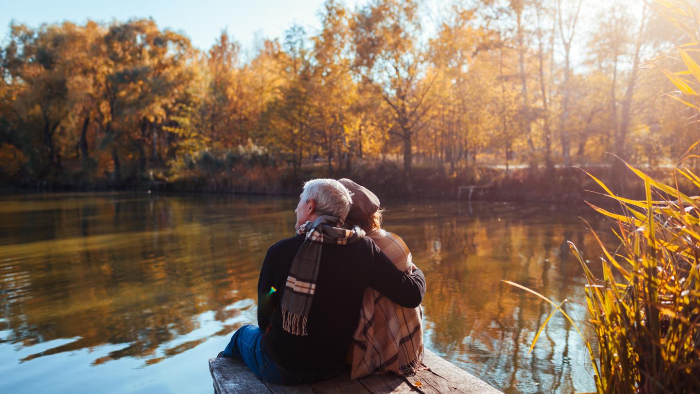 Couple relaxing and enjoying beautiful autumn day at their pond